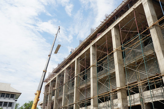 Crane is lifting a prestressed floor to installation building. And scaffold for supporting the building structures on the construction site. 