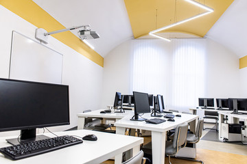 office room with computer tables with keyboard and mouse with a board and a projector