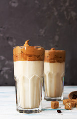 Dalgona coffee. Korean coffee in two glasses with brown sugar, coffee on gray background. Drink cold milk.