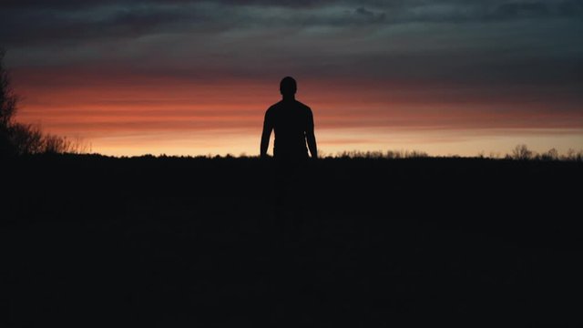 Canada - A man walking in the dark landscape towards the sunset - Wide shot