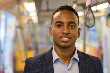 Fototapeta premium Face of happy young handsome African businessman smiling inside the train