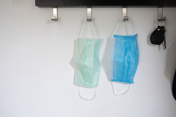 Two sanitary masks hanging on the hook, white and blue color.