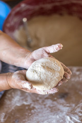 Female hands kneading dough on wooden table