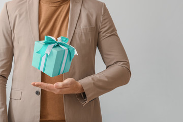 Man with beautiful gift on grey background