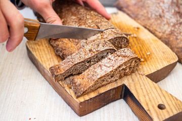 Whole wheat flour, rye brown baked dietary healthy bread. Woman hands cut bread loaf
