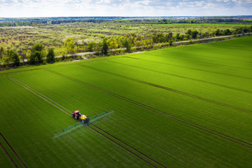Farmland in Europe, tractor spraying pesticides - obrazy, fototapety, plakaty