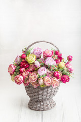 Fototapeta na wymiar Beautiful bouquet of peonies in an antique basket on a wooden floor