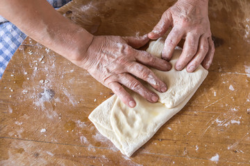 Woman in a black chef's apron roll out the dough for preparing Turkish pancake. 
Woman rolls out...