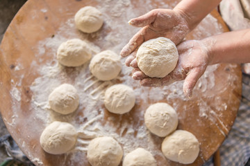 Female hands kneading dough on wooden table
