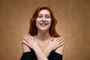 Studio large photo portrait of Caucasian young actress woman with long red hair on a beige background. Model poses with a smile and grimace.