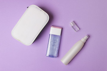 white make-up box and bottles with tonic on purple colored paper background