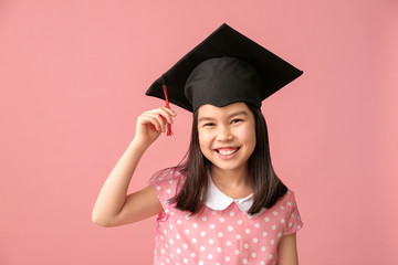 Little girl in graduation hat on color background