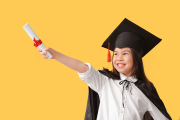 Little girl in graduation hat and with diploma on color background