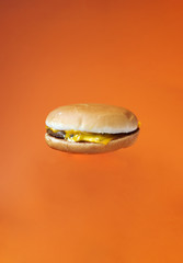 Hamburger in the air. Bright oramge background for text and design