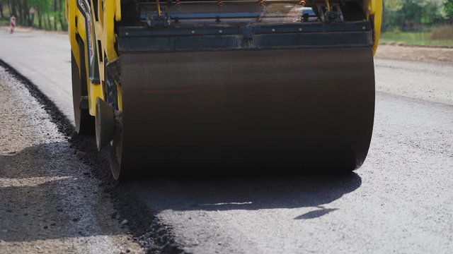 Roller machines make new asphalt roads. The asphalt paver squeezes hot asphalt.
