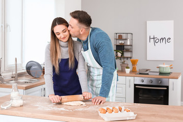 Happy couple making dough together in kitchen