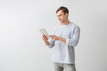 Obraz premium Young man with tablet computer on light background