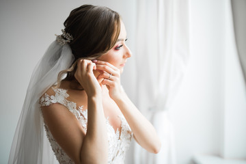 Obraz na płótnie Canvas Beautiful bride wearing fashion wedding dress with feathers with luxury delight make-up and hairstyle, studio indoor photo shoot