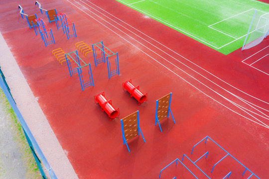 Playground with obstacle course on a sports court next to treadmills.