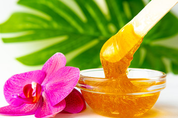 depilation and beauty concept - sugar paste or wax honey for hair removing flows down from wooden...