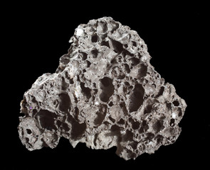 Sample of Volcanic Black Lava isolated on black background. Mineral of volcanic origin