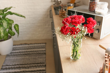 Vase with bouquet of beautiful flowers on table in kitchen