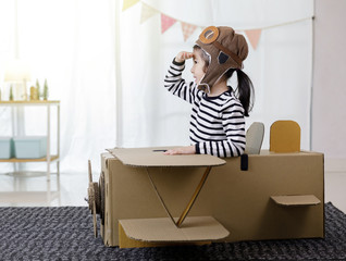 Asian little child girl playing with cardboard toy airplane handicraft isolated in home with copy space for your text, Creative with family and dreaming of flying concept