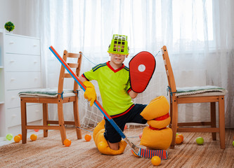 A child boy plays hockey at home having made a form with his own hands from improvised home tools...