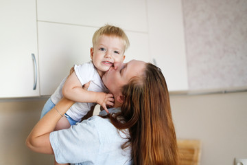 Caucasian woman mom hugs her toddler son in kitchen