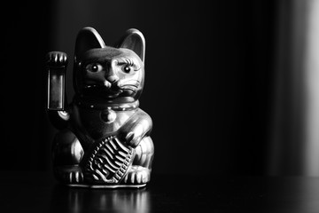 Maneki Neko, the Lucky Cat, covered with dust, black and white. Concept of fast passing time and...