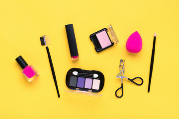 Set of professional decorative cosmetics, makeup tools and accessory of trendy pink color isolated on yellow background Flat lay Top view