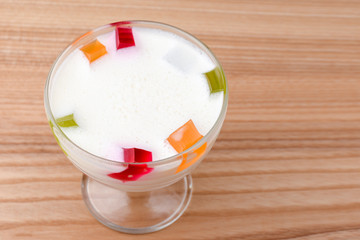Milk and fruit jelly in a glass served on light wooden table. Traditional dessert