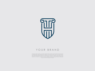 a blue business logo that looks like a shield and has representations of an ancient column, letter h and t 