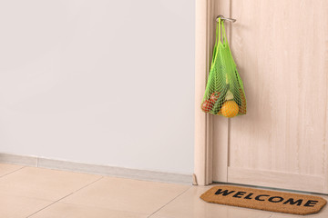 Bag with products left by courier of food delivery service hanging on door. Concept of epidemic