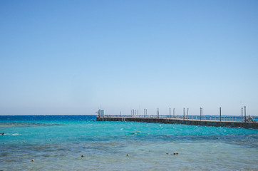 pier leading to the sea on a sunny day/empty pier overlooking the sea on a sunny day