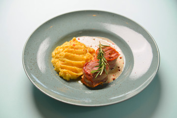 Beef meat pieces with mashed potato, onion gravy and spices. Served on a blue plate over blue mint background.
