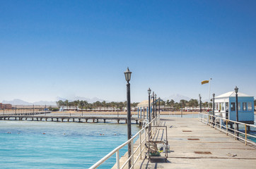 pier leading to the sea on a sunny day/empty pier overlooking the sea on a sunny day