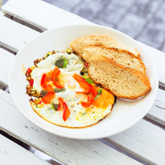 Smażone jajka, omlet, potrawa na śniadanie, biały talerz, dodatki sałatka i warzywa oraz pieczywo. - obrazy, fototapety, plakaty