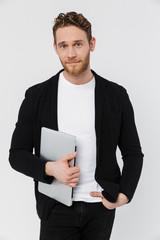 Image of handsome pleased man in jacket smiling and holding laptop