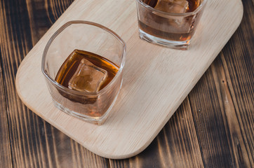 Two Glasses of cognac with ice cubes on a wooden table/Two Glasses of cognac with ice cubes on a wooden table. Top view