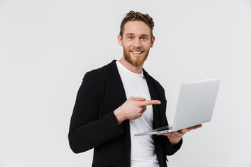 Image of happy man in jacket using and pointing finger at laptop