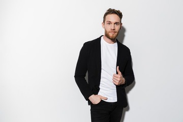 Image of unshaven confident man in jacket posing and looking at camera