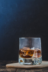 Glass of cognac with ice cubes on a wooden bar/Glass of cognac with ice cubes on a wooden bar,...