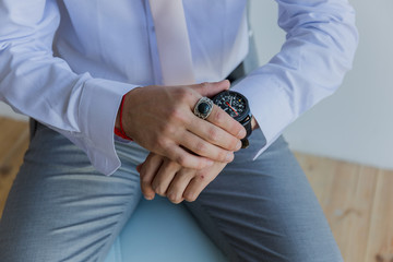 a man in a shirt puts a watch on his hand