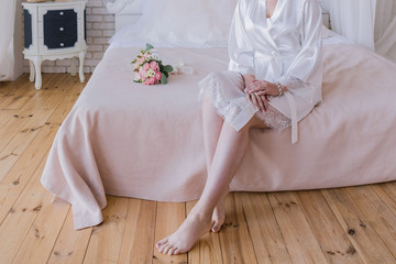 Fototapeta na wymiar the bride in a peignoir holds a wedding dress