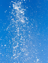 Splashing water from a fountain on a background of blue sky