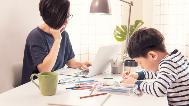 Social Distancing & Work From Home, Homeschool Asian Little Boy Draw And Color While Stressed Mother On Phone, Look At Computer Laptop Working During Pandemic Of Covid-19, Quarantine And City Lockdown