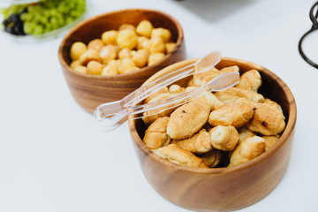 Small,crispy croissants lie in a plate. On top of the plate are tongs for them