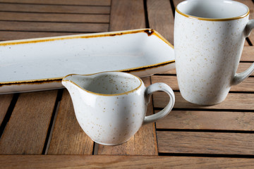 White porcelain tableware on wooden garden table