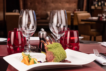 Piece of lamb rack with bone roasted with green herb, bread, sweet potatoes puree, baby vegetables